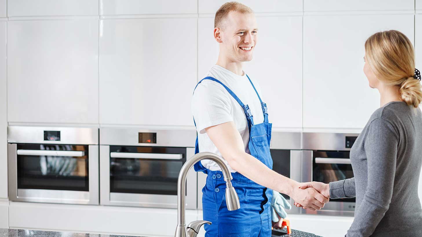 Handwerker schüttelt Hand mit Frau in Küche